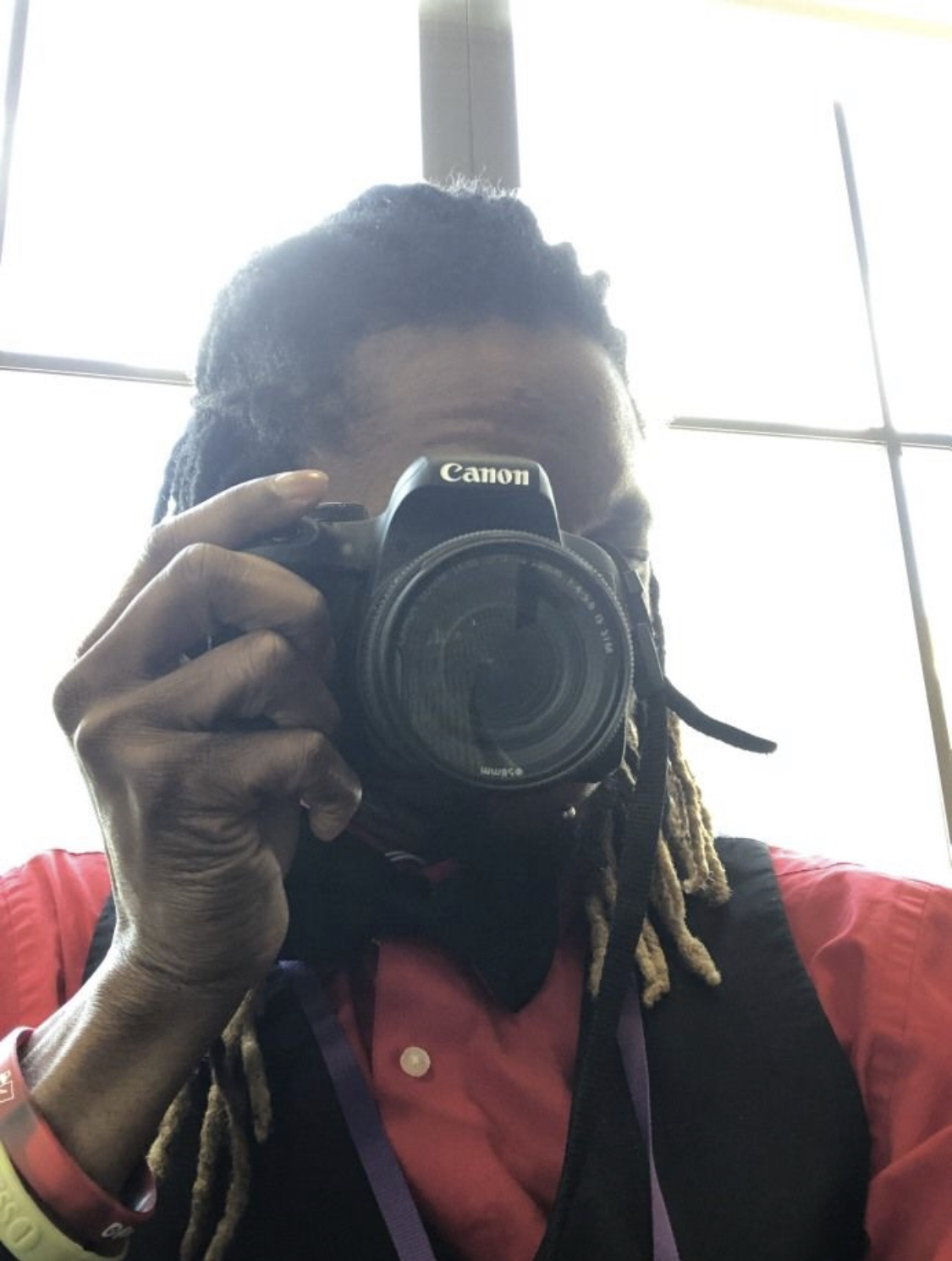 Image of Terell Kahn Douglas-Williams holding Canon DSLR camera up to his eye as if he is taking your picture.